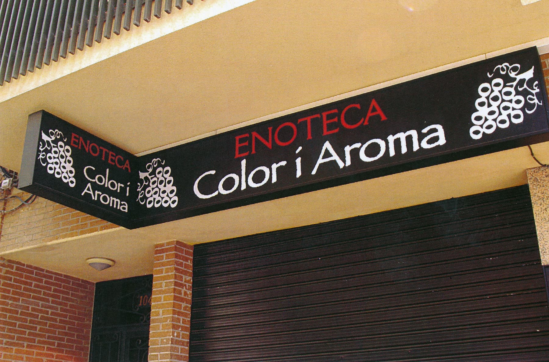 Rótulo de la enoteca Color i Aroma en lona impresa sobre fachada de ladrillo
