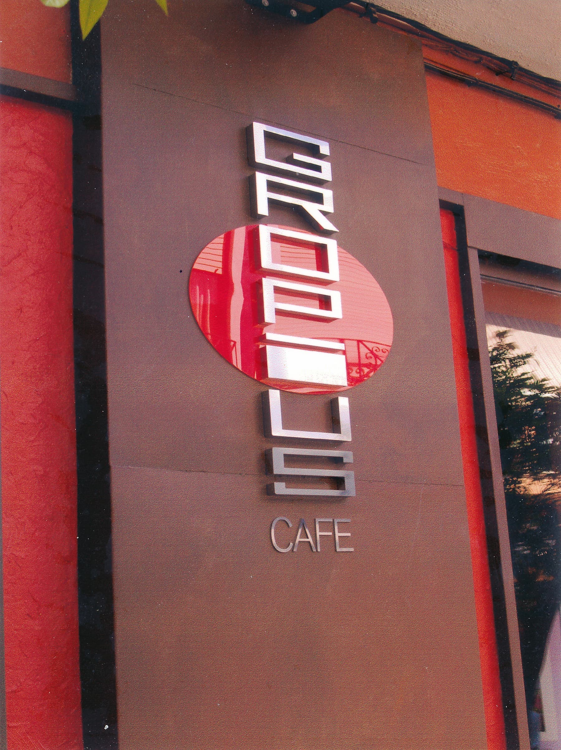 Letras corpóreas metálicas de Krobus Café sobre fachada granate