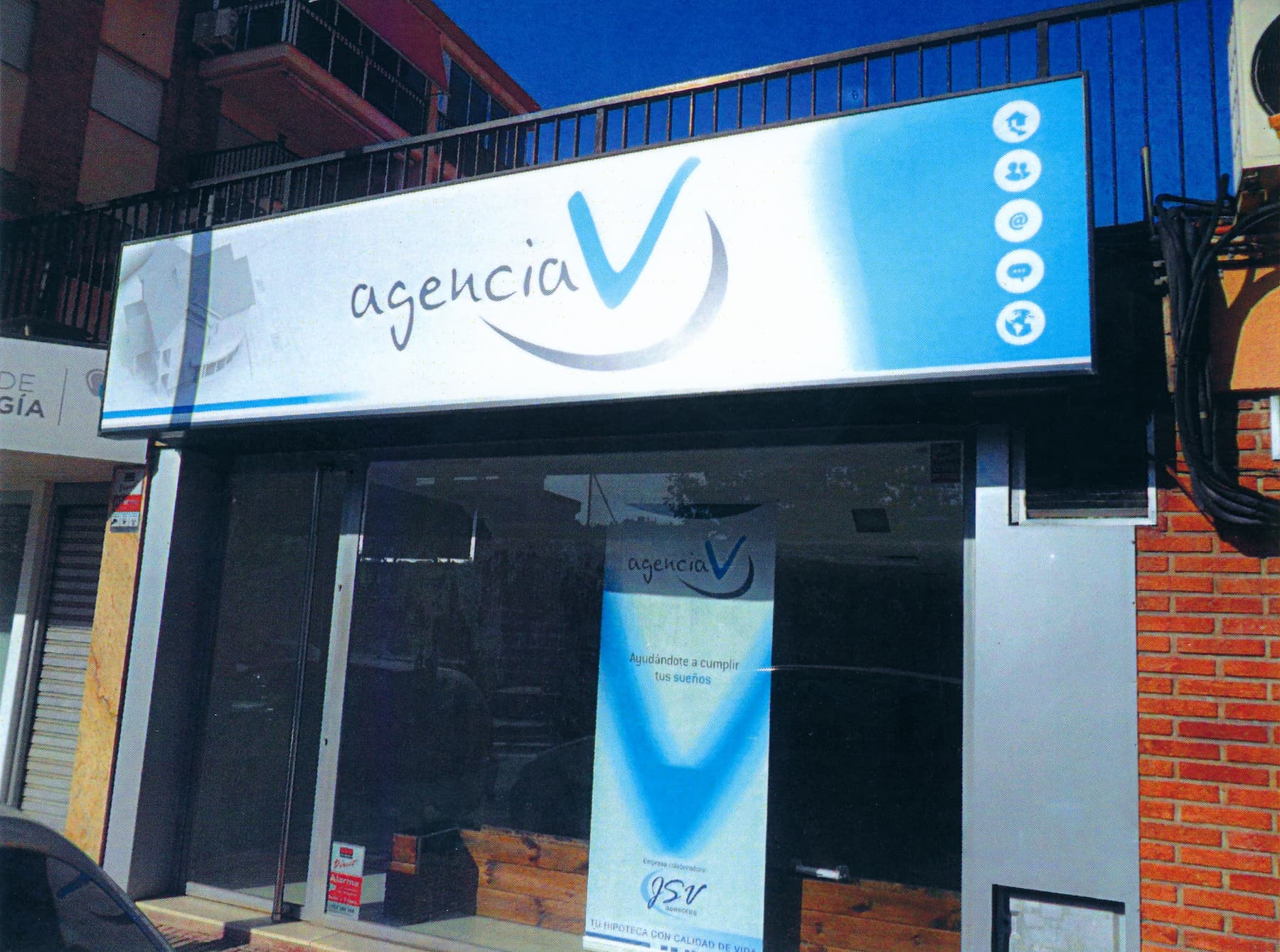 Fachada corporativa azul de Agencia V con logotipo en vinilo