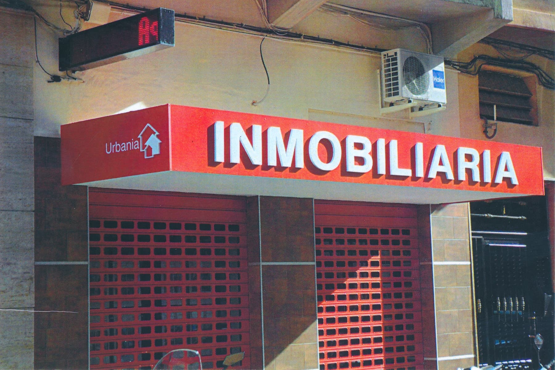 Rótulo luminoso de una inmobiliaria con letras blancas sobre fondo rojo